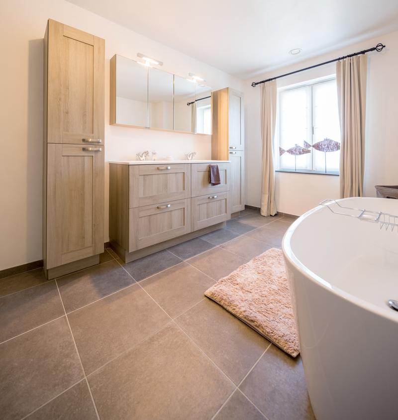 A bright bathroom with a freestanding bath, a double vanity and a curtained window